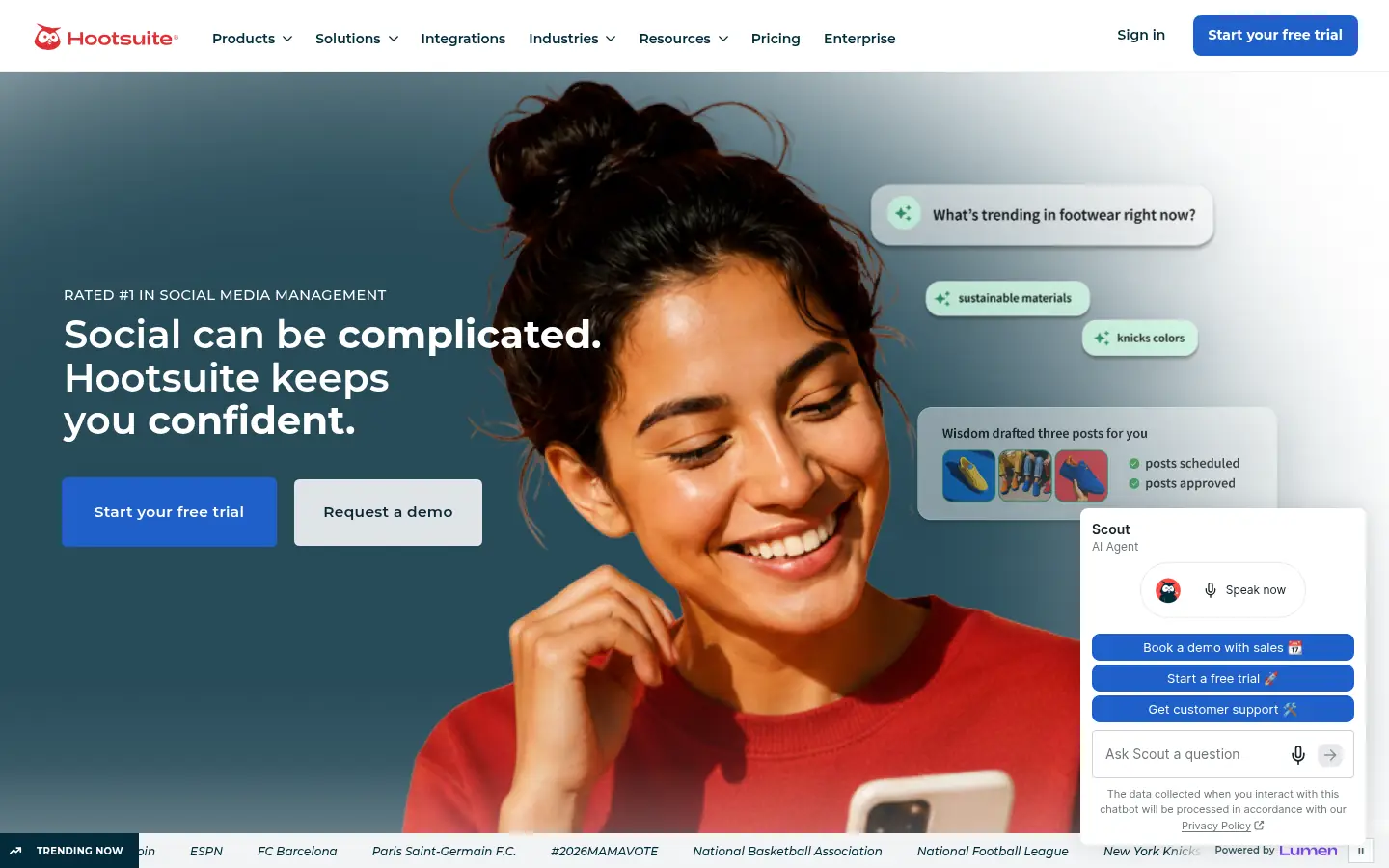 Hootsuite website, showing a social media management banner beside a photo of a person holding a phone