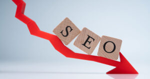 A wood block of SEO above a red arrow going down